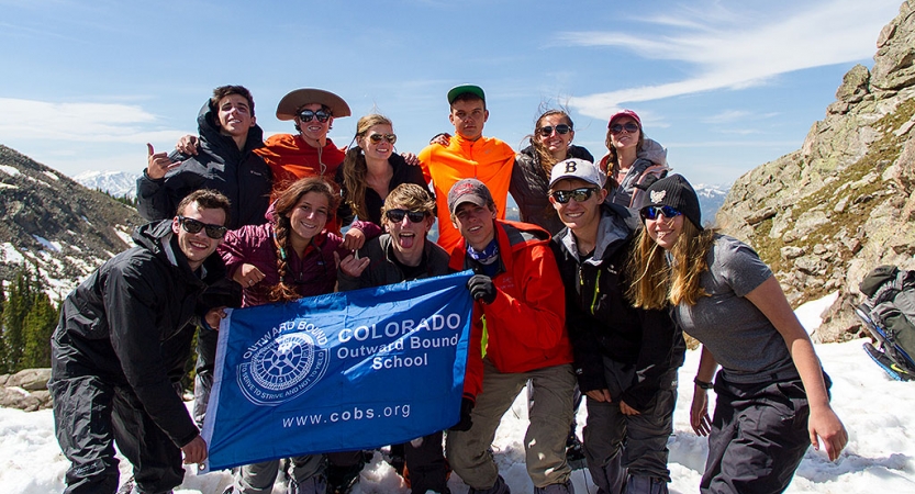 a group of students smile at the camera while standing on a snowy and rocky landscape